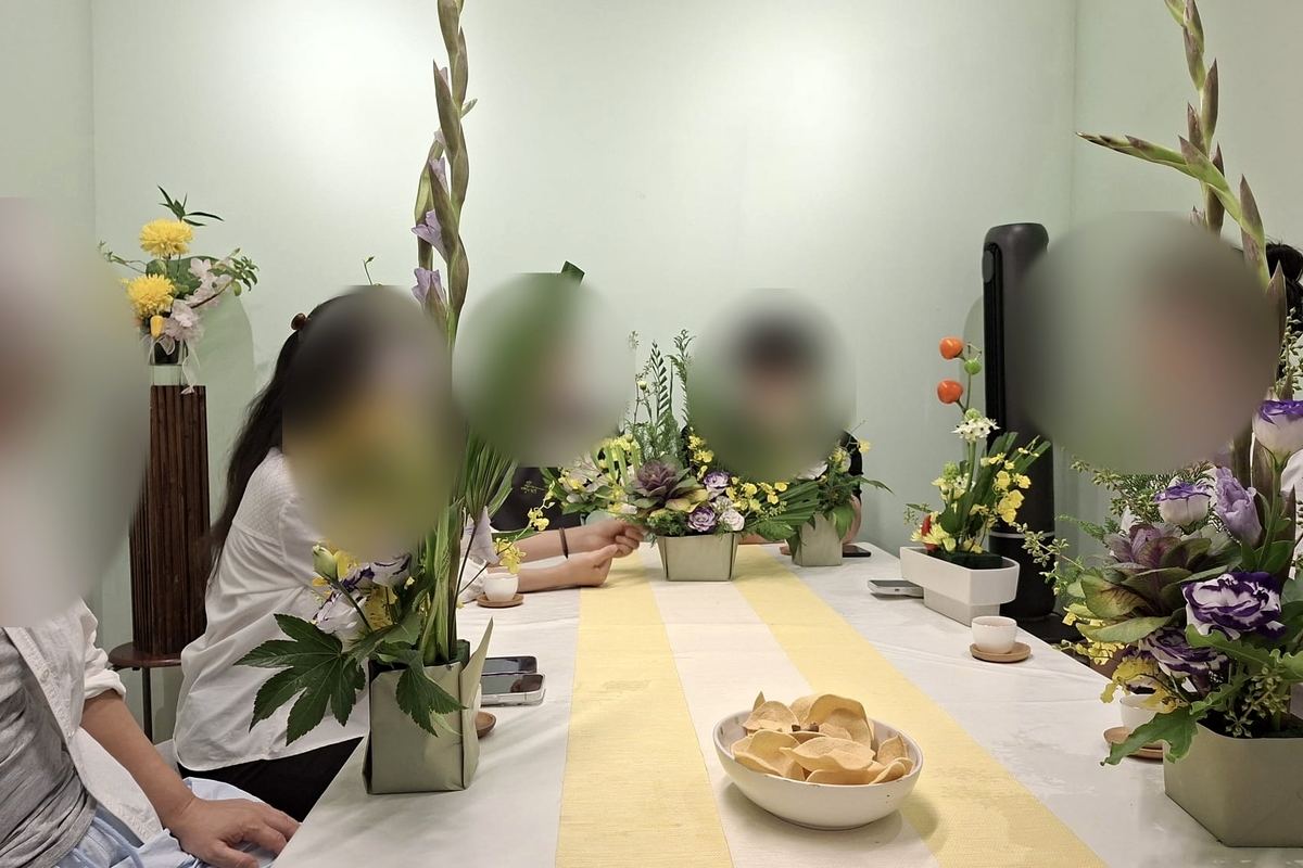 插花课：学员围坐长桌，桌上摆满插花作品